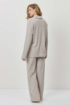 Woman wearing a beige suit standing against a white background