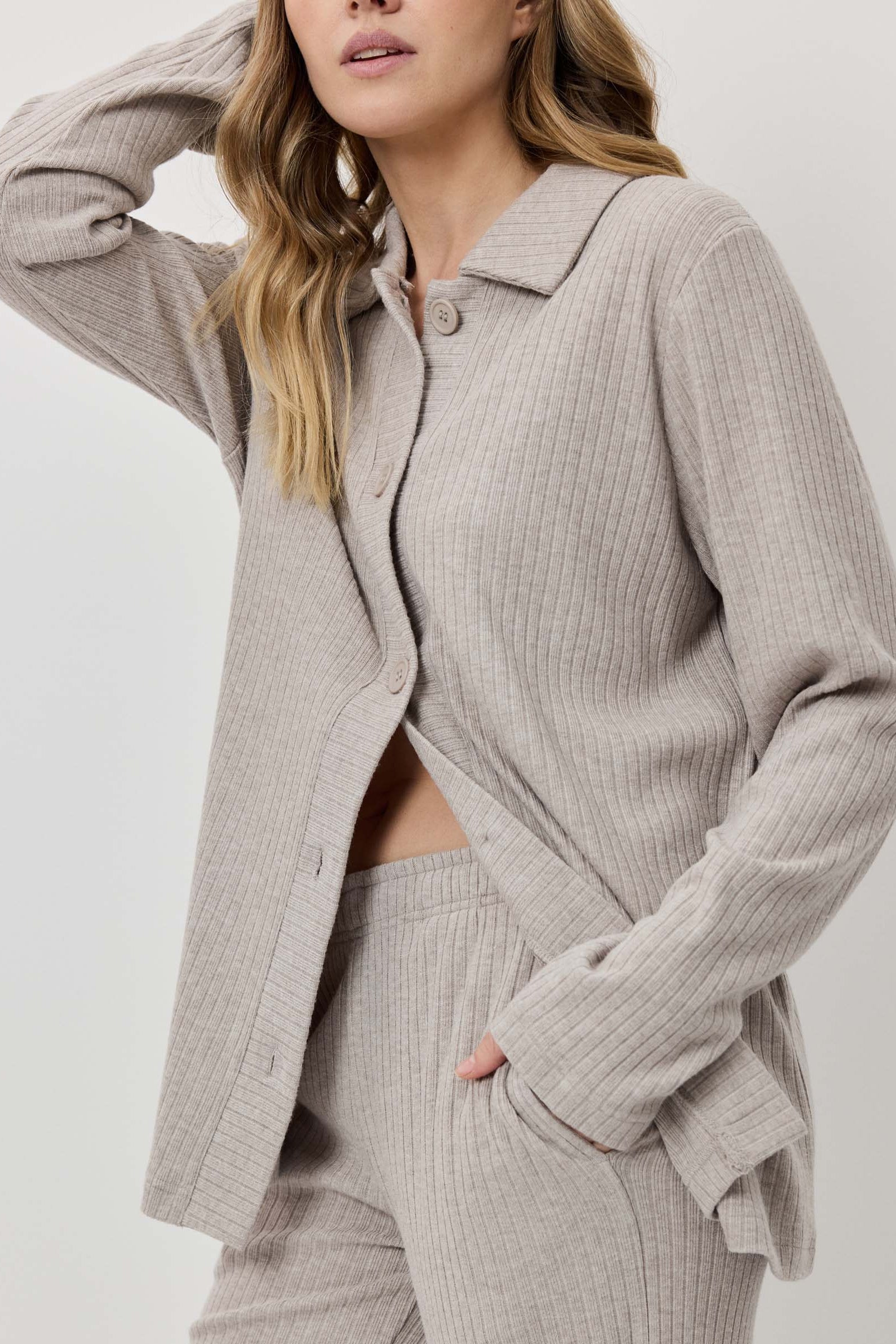 Person wearing a light gray ribbed knit suit on a white background