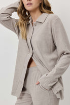 Person wearing a light gray ribbed knit suit on a white background