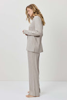 Woman wearing a gray suit standing against a white background