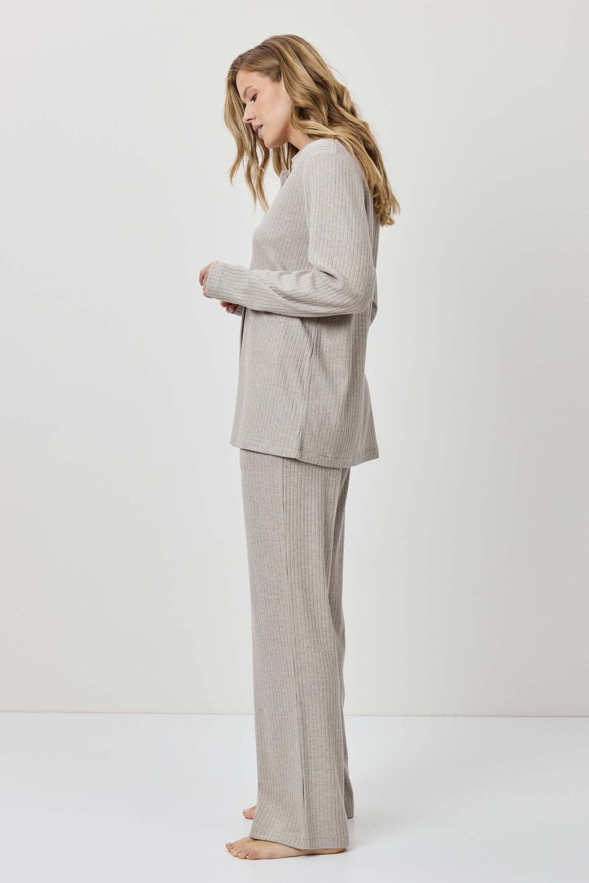 Woman wearing a gray suit standing against a white background