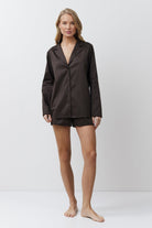 Woman wearing a dark brown pinstripe pajama set on a white background