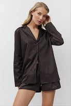 Woman wearing a brown pajama set against a white background