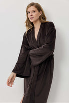 Woman wearing a dark brown robe against a white background