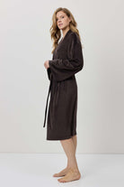 Woman wearing a brown robe against a white background