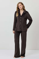 Woman wearing a brown pajama set against a white background