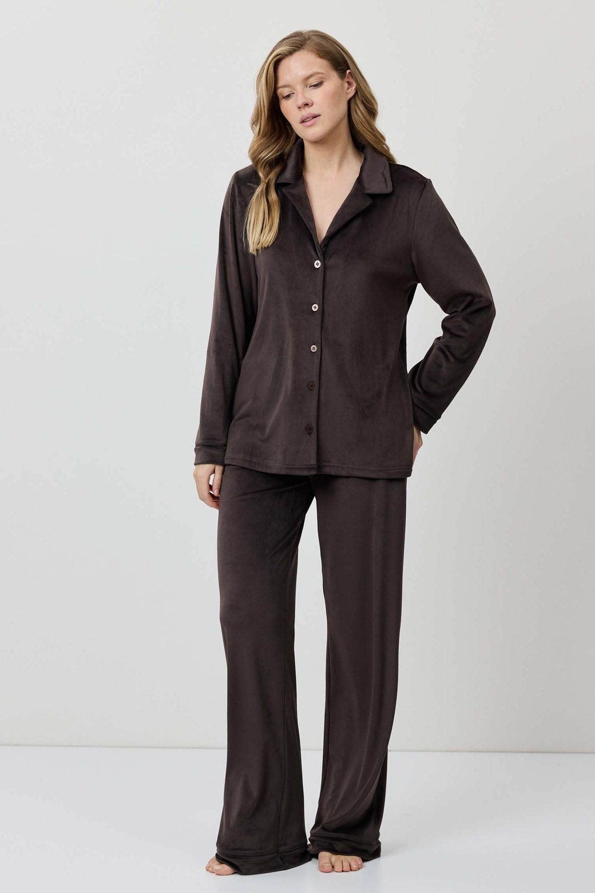 Woman wearing a brown pajama set against a white background