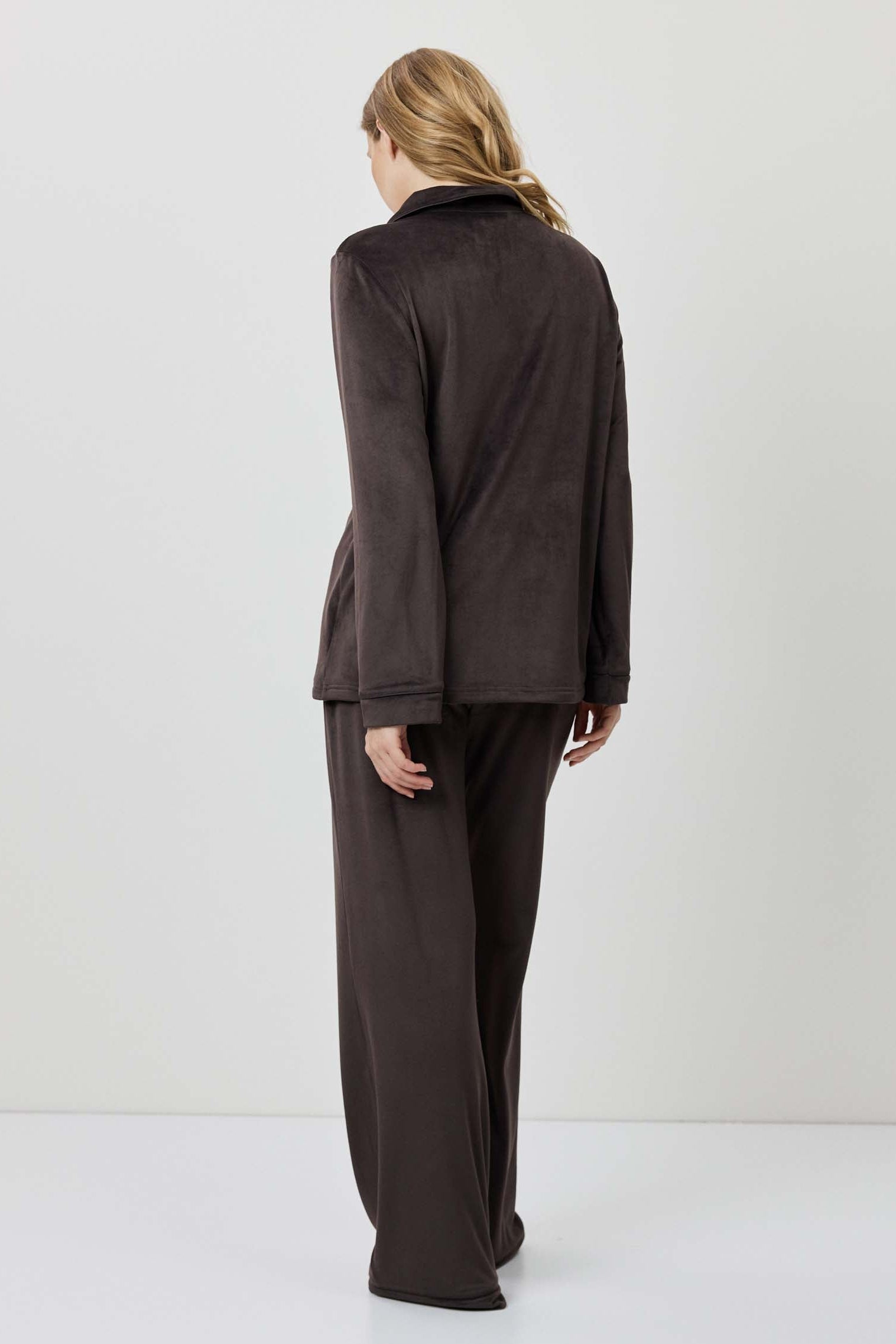 Person wearing a brown outfit standing against a white background