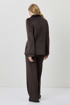 Person wearing a brown outfit standing against a white background