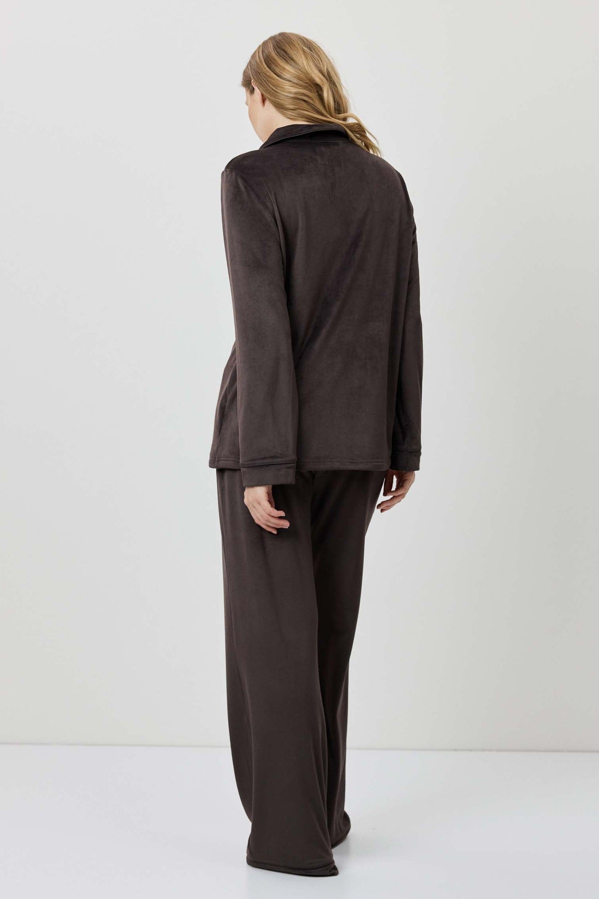 Person wearing a brown outfit standing against a white background