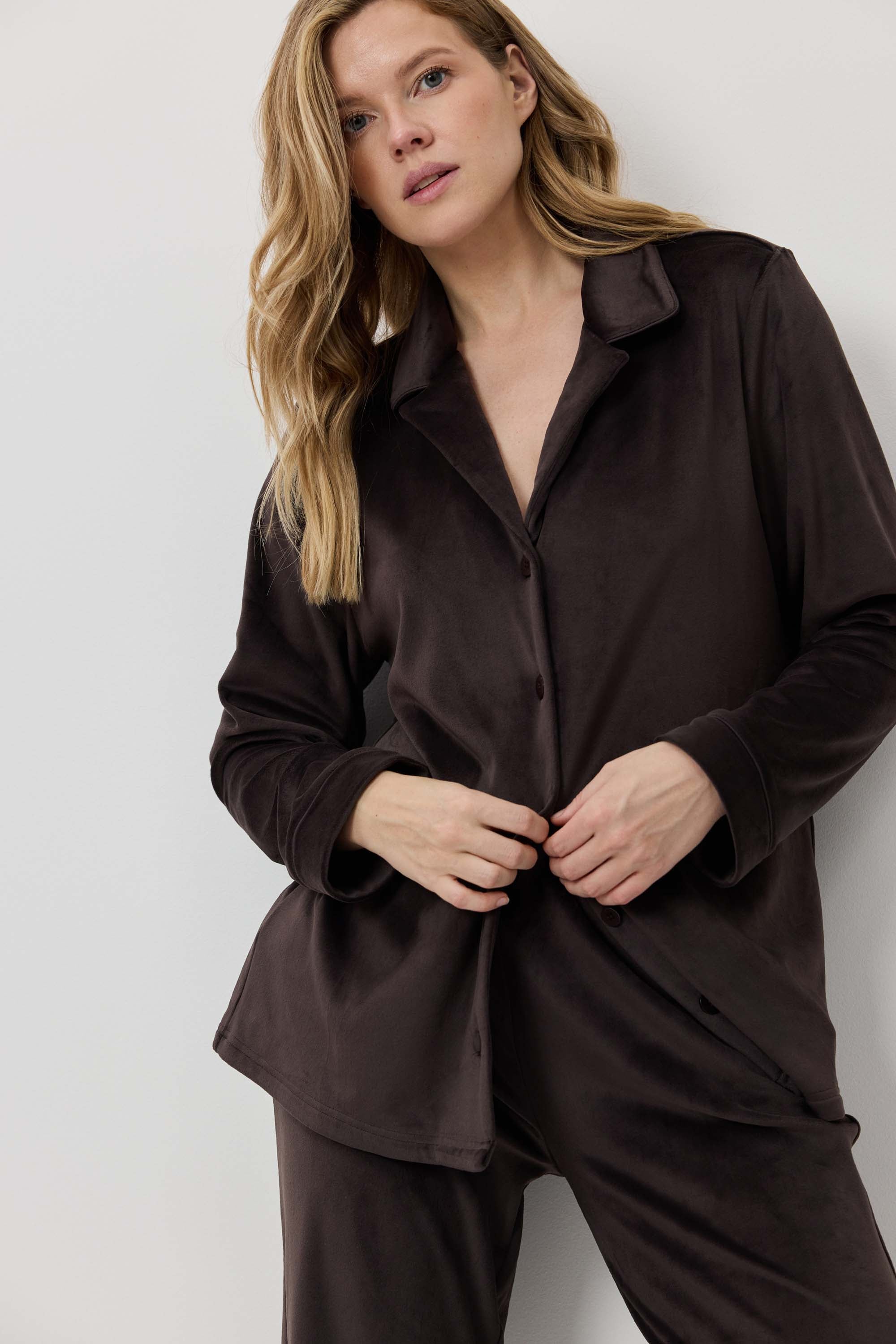 Woman wearing a brown pajama set against a white background