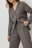 Woman wearing a houndstooth patterned outfit with a belt on a plain background