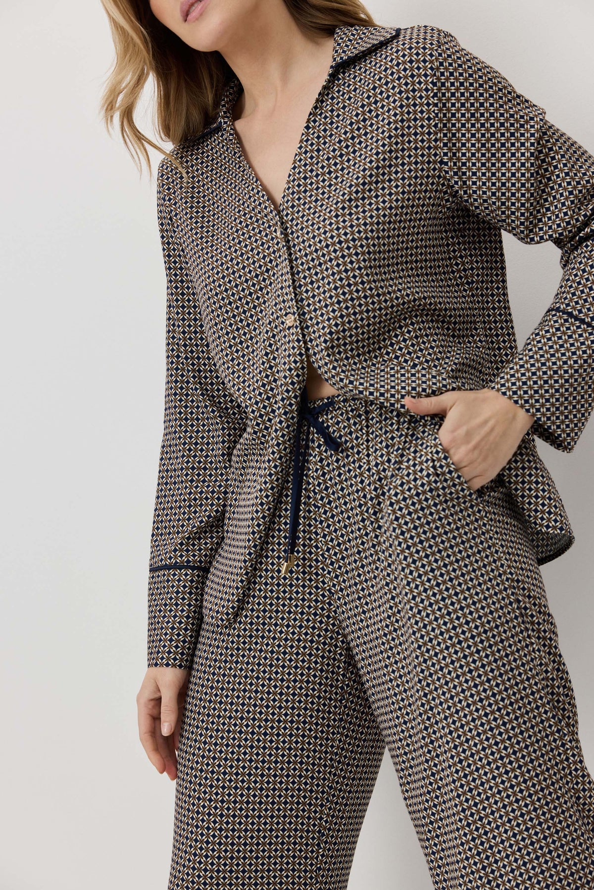 Woman wearing a houndstooth patterned outfit with a belt on a plain background