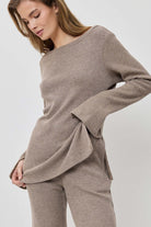 Woman wearing a beige sweater and pants on a white background
