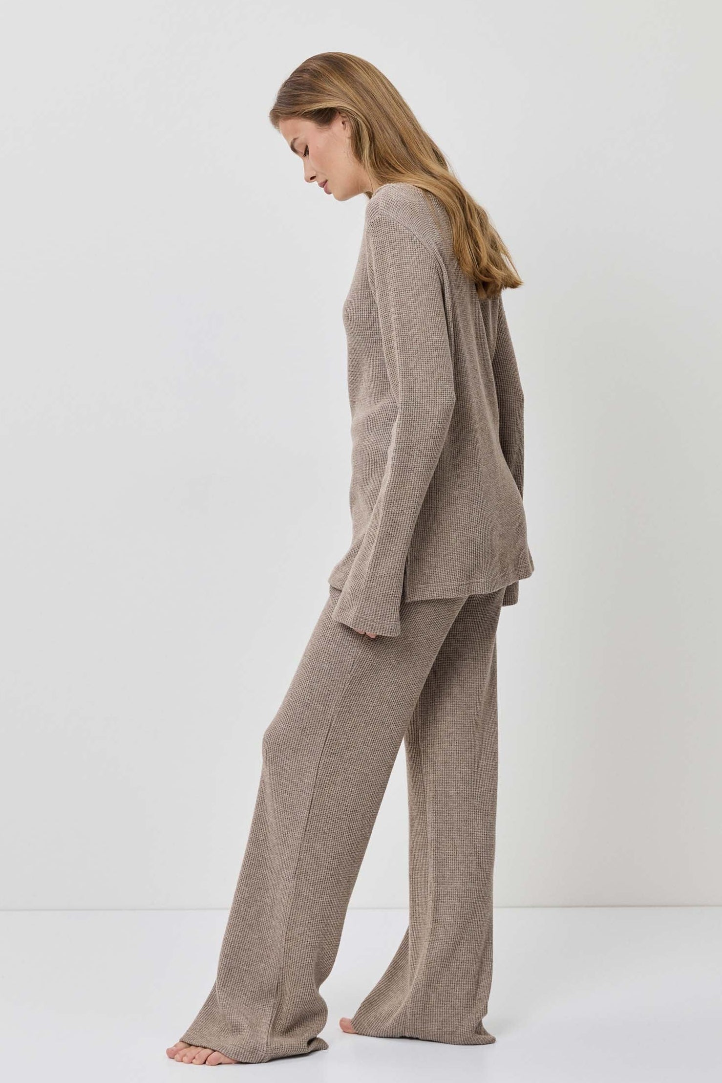 Woman wearing a beige suit standing against a white background