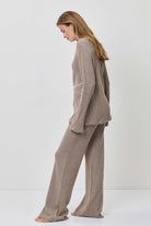 Woman wearing a beige suit standing against a white background