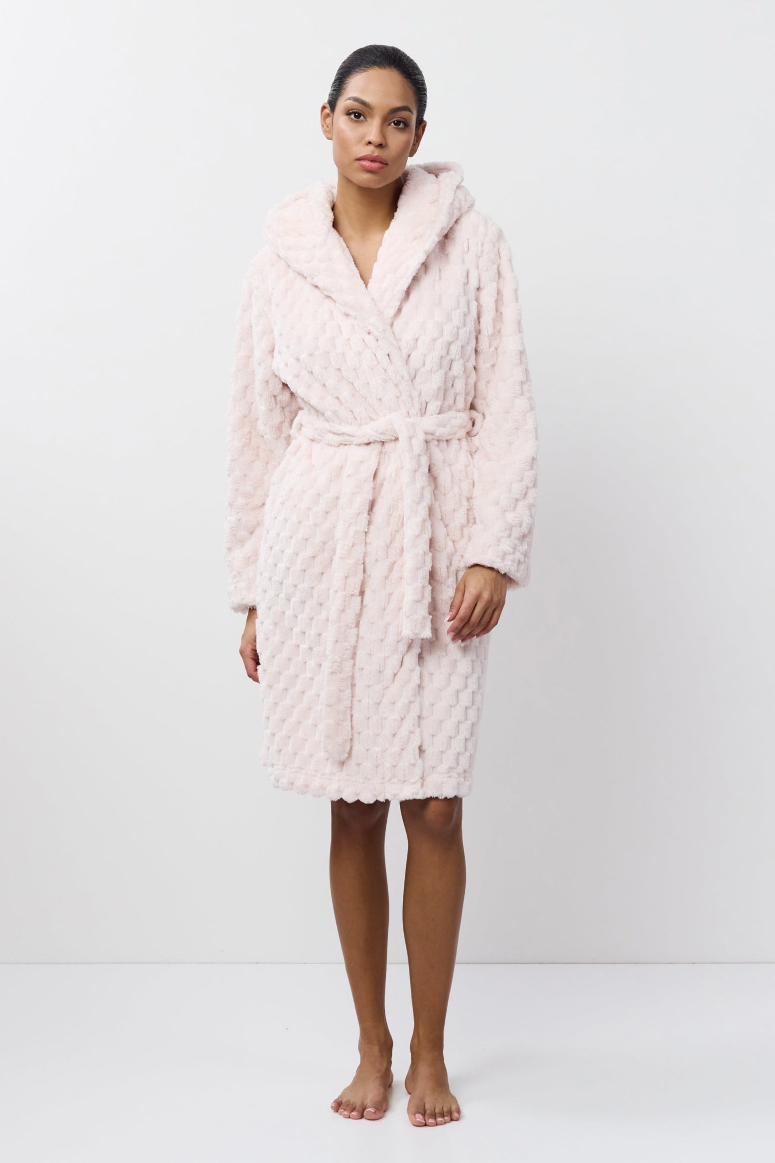 Person wearing a pink quilted bathrobe on a white background
