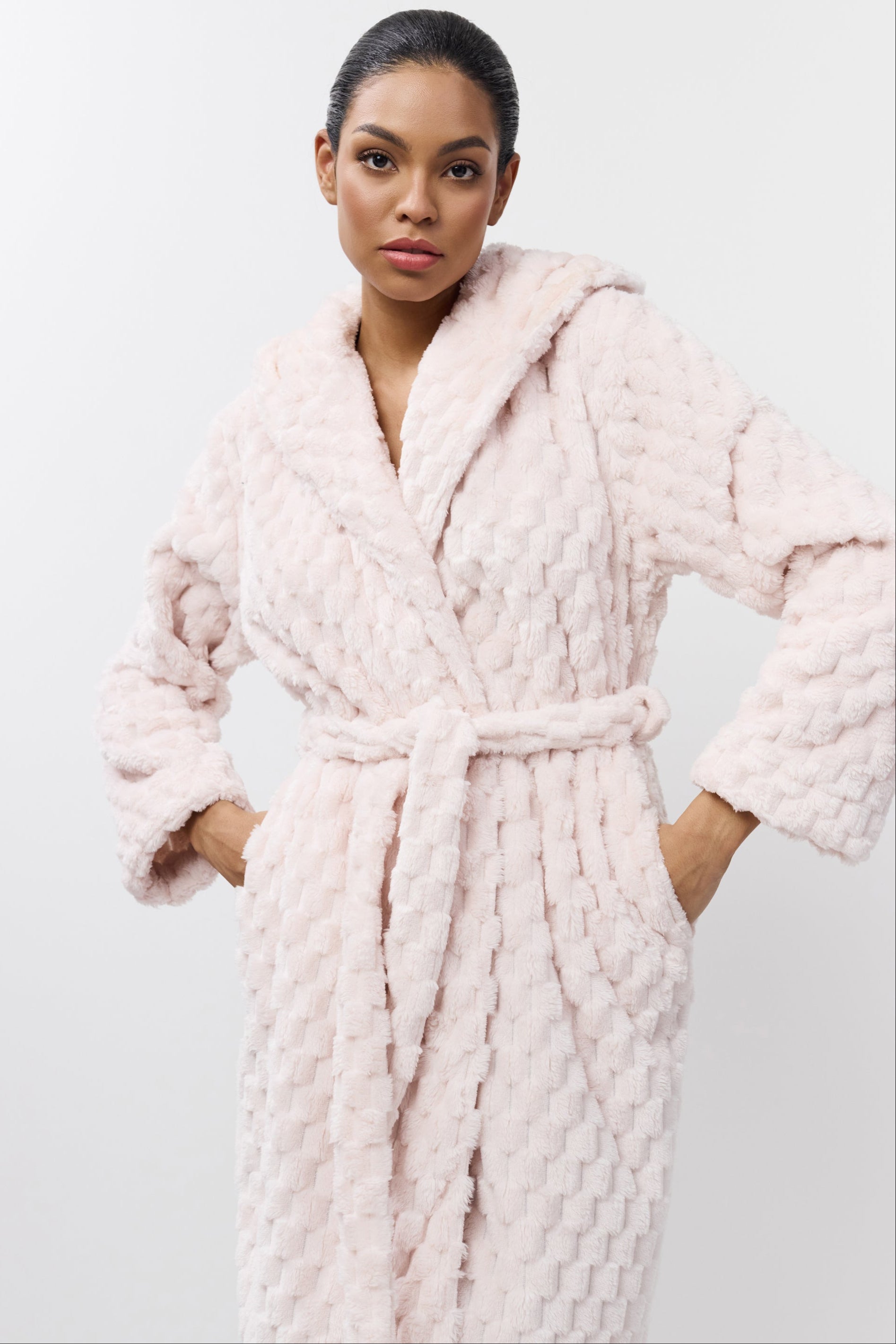 Woman wearing a pink textured bathrobe against a white background