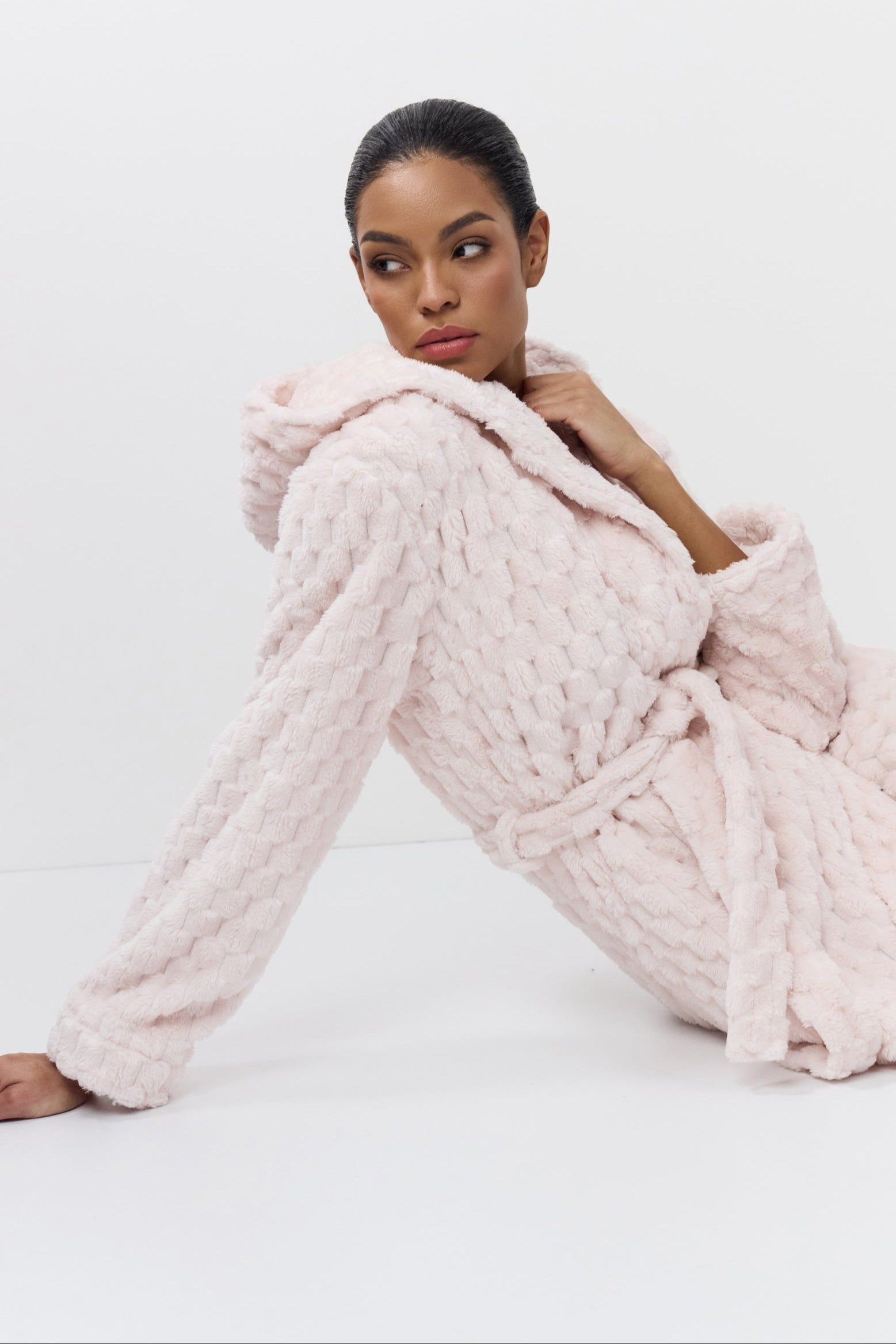 Woman wearing a pink textured bathrobe on a white background