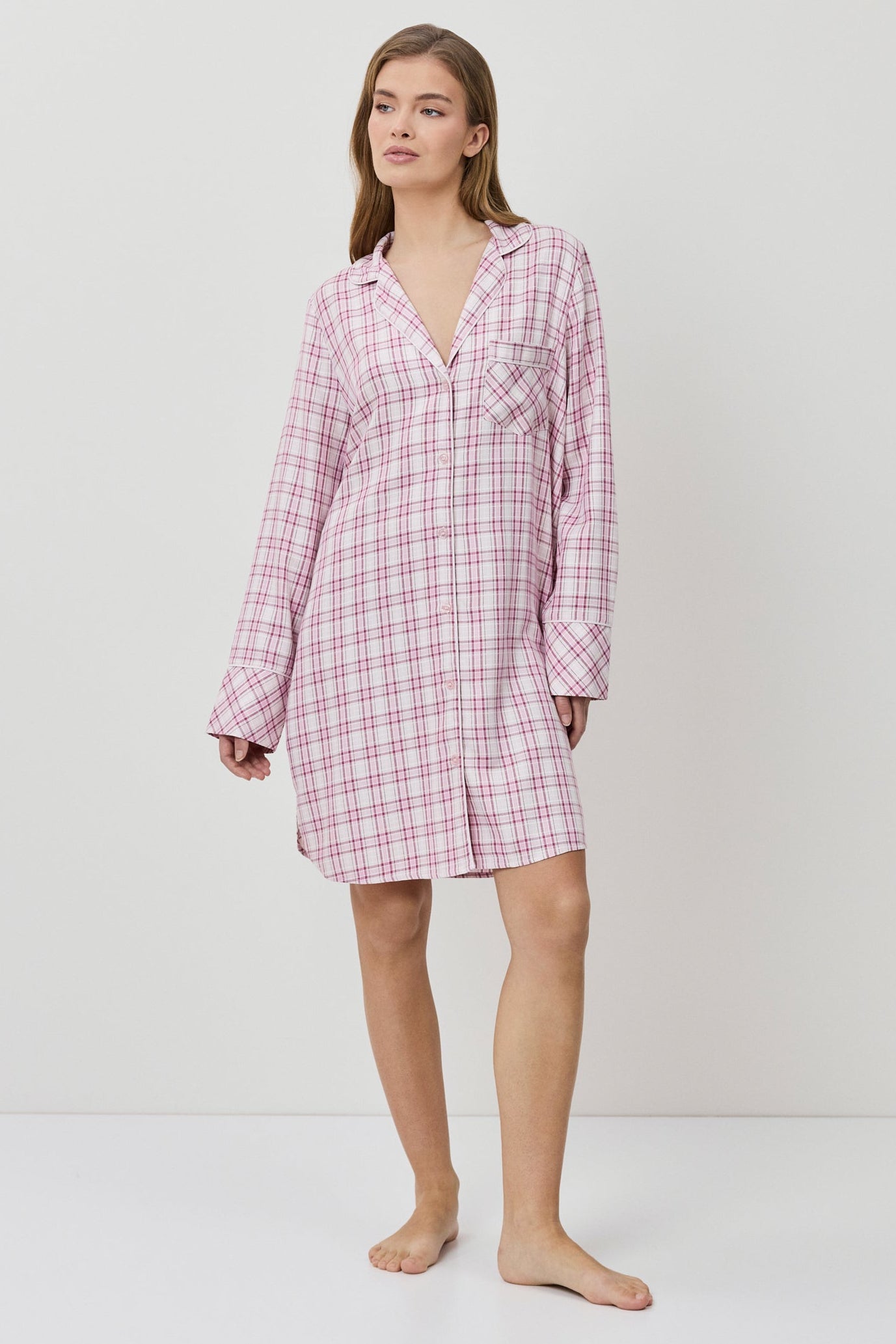 Woman wearing a pink checkered nightshirt on a white background