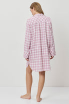 Person wearing a pink and white checkered nightshirt on a plain background