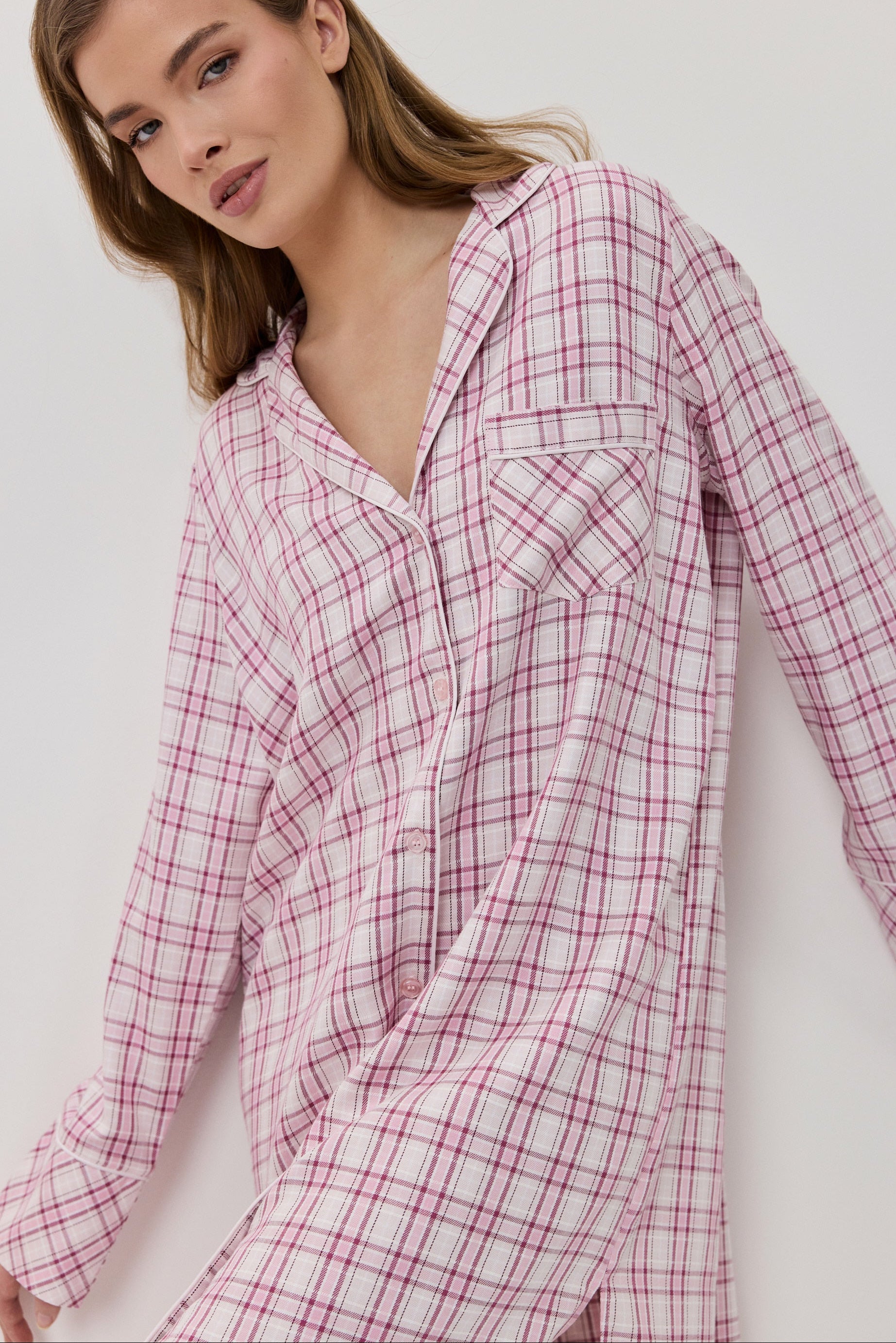 Woman wearing a pink and white checkered shirt against a white background