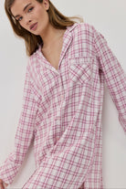 Woman wearing a pink and white checkered shirt against a white background