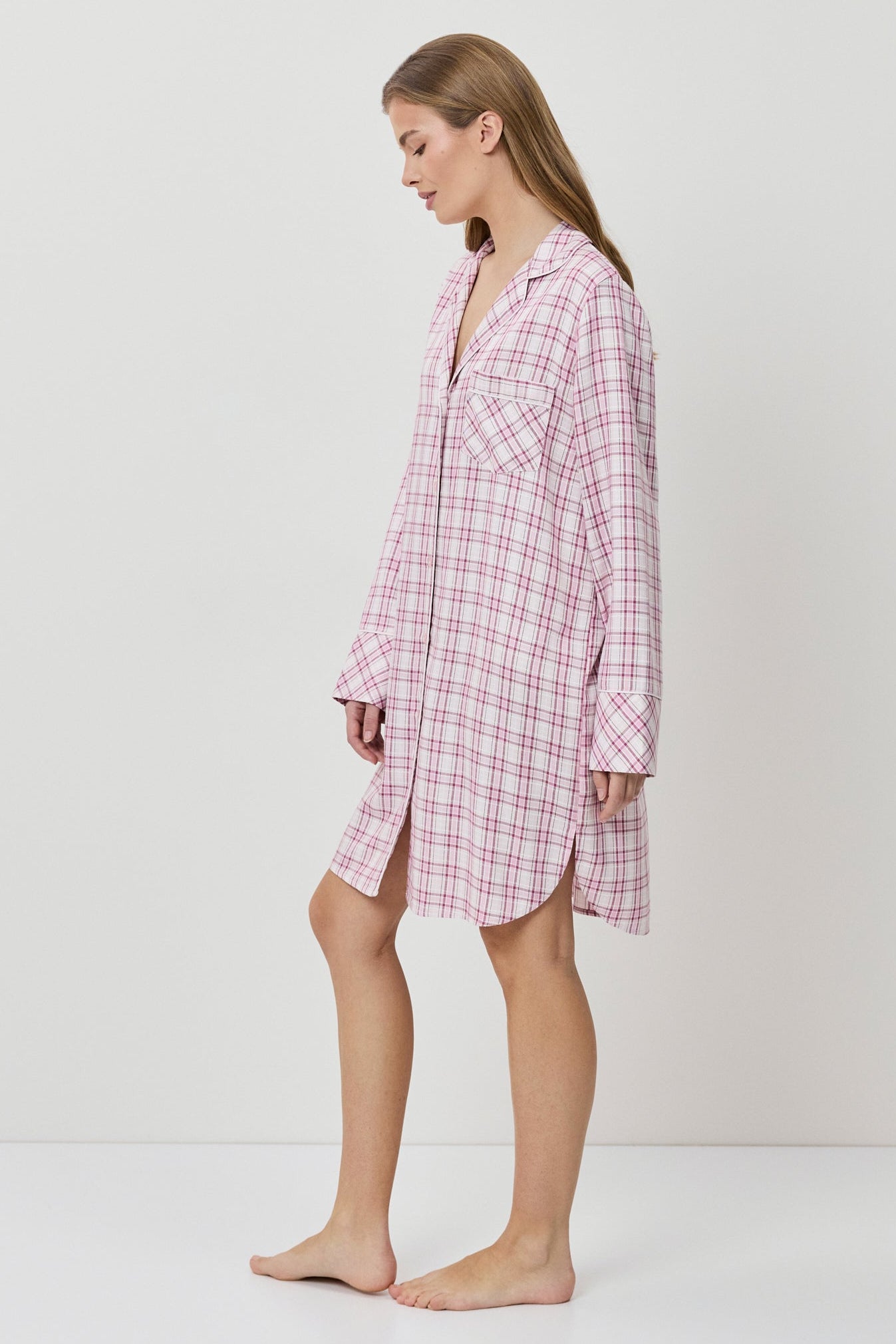 Woman wearing a pink checkered nightshirt on a white background