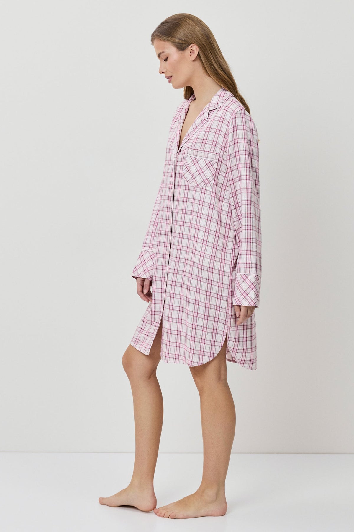 Woman wearing a pink checkered nightshirt on a white background