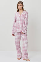 Woman wearing pink checkered pajamas on a white background
