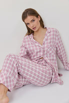 Woman wearing a pink plaid robe sitting on a white surface.