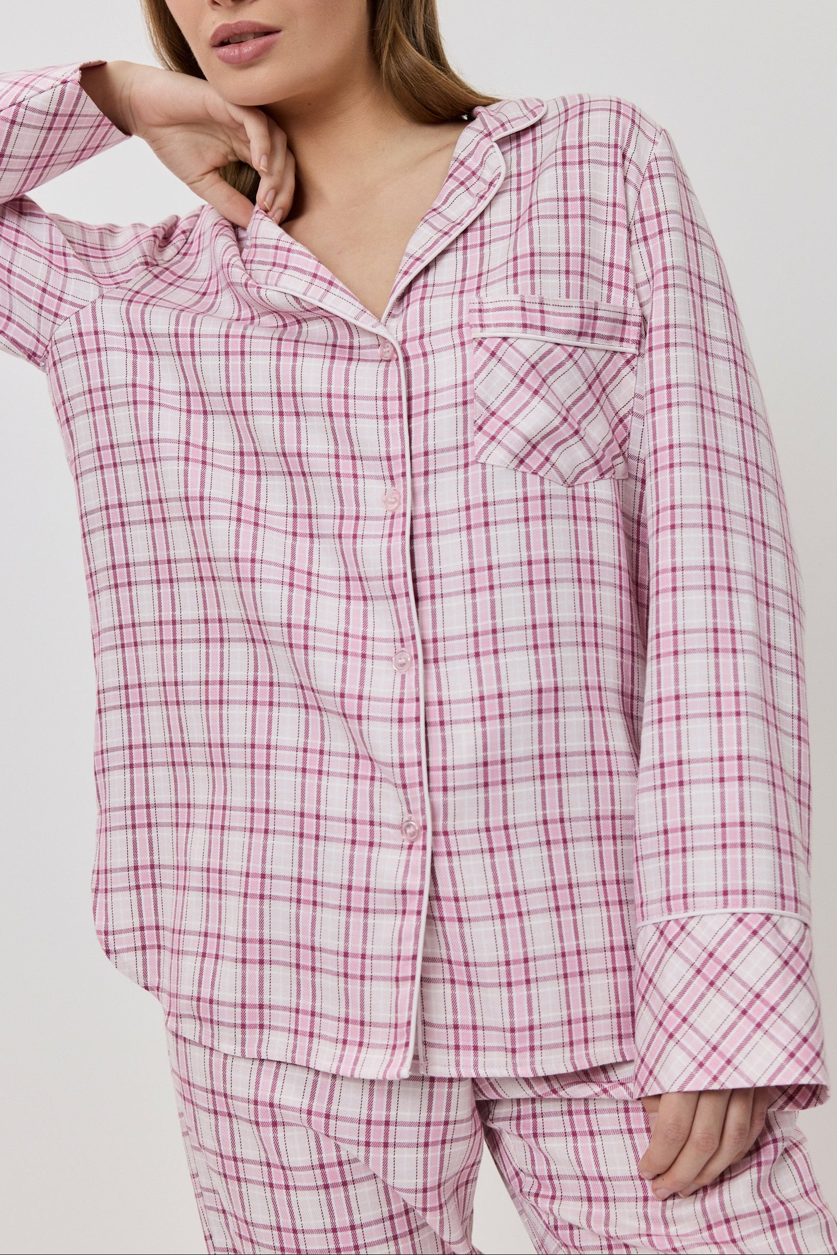 Woman wearing a pink and white checkered pajama set on a plain background