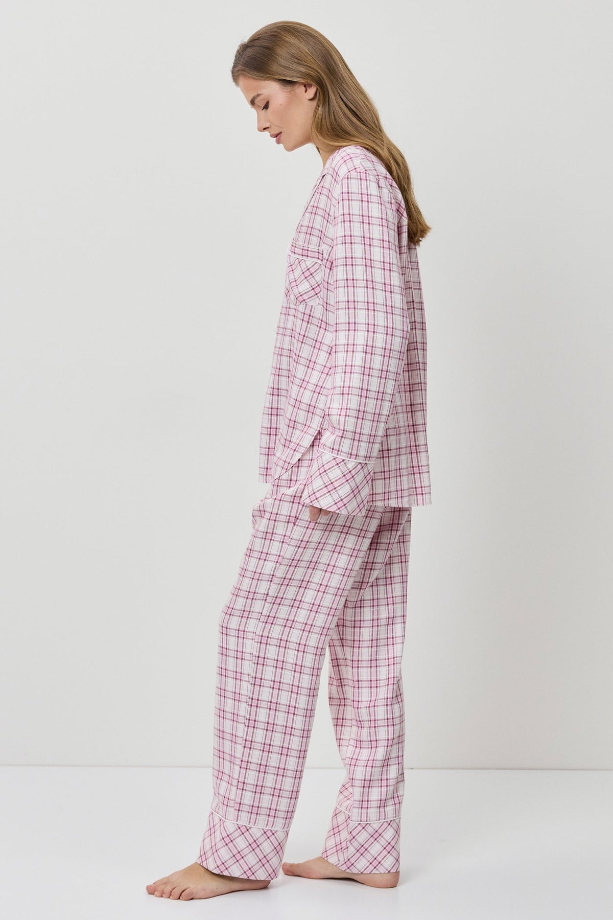 Woman wearing pink checkered pajamas on a white background