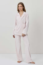 Woman wearing a light pink pajama set against a white background