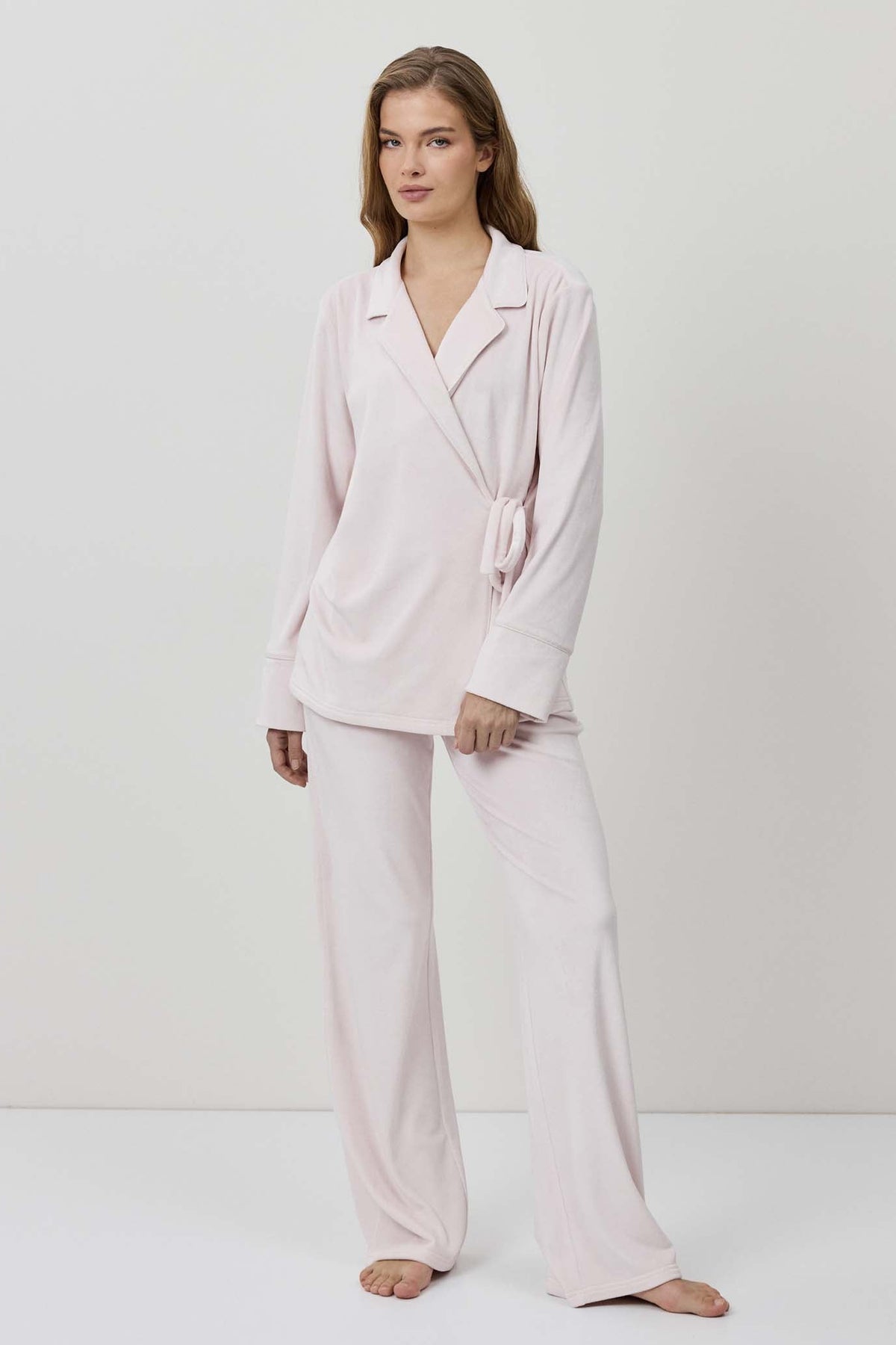 Woman wearing a light pink pajama set against a white background