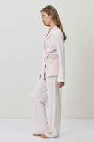 Woman wearing a light pink pajama set on a white background
