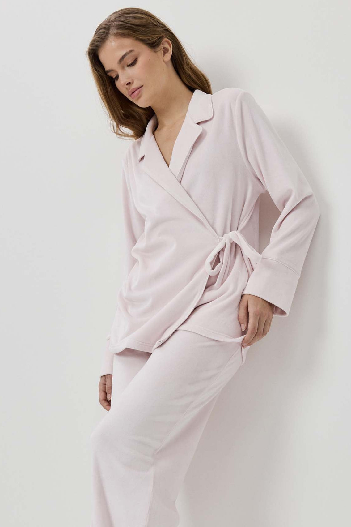 Woman wearing a light pink robe against a white background