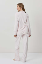 Woman wearing a light pink pajama set against a white background