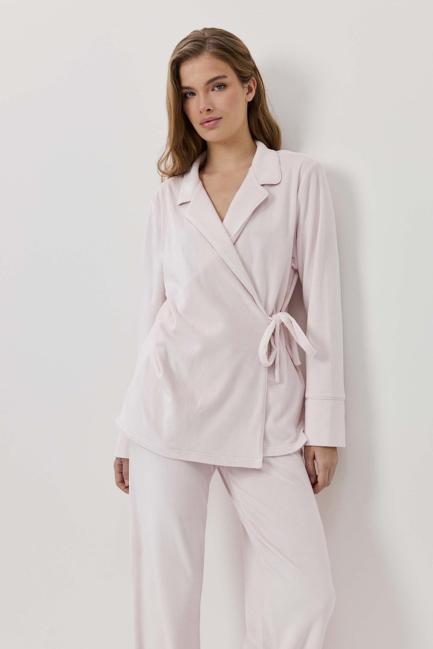 Woman wearing a light pink suit against a white background