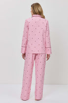 Person wearing a pink pajama set with hearts on a white background