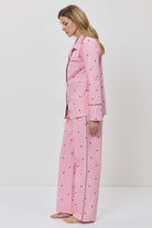 Person wearing a pink pajama set with hearts on a white background