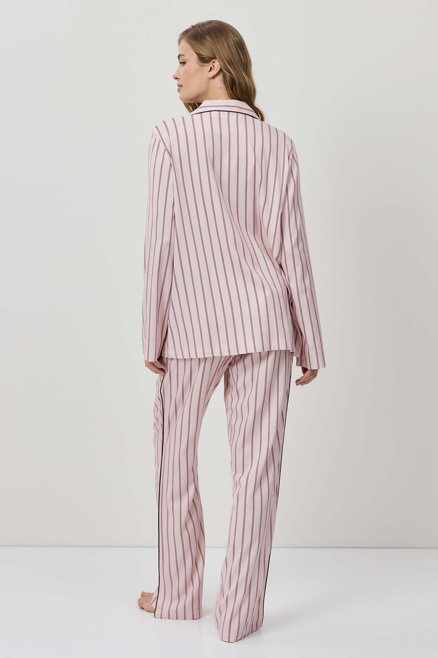 Woman wearing a pink and white striped pajama set on a white background