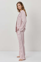 Woman wearing a pink striped pajama set against a white background