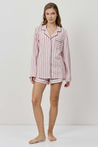 Woman wearing a pink striped pajama set on a white background