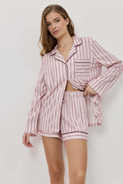 Woman wearing a pink striped pajama set against a white background
