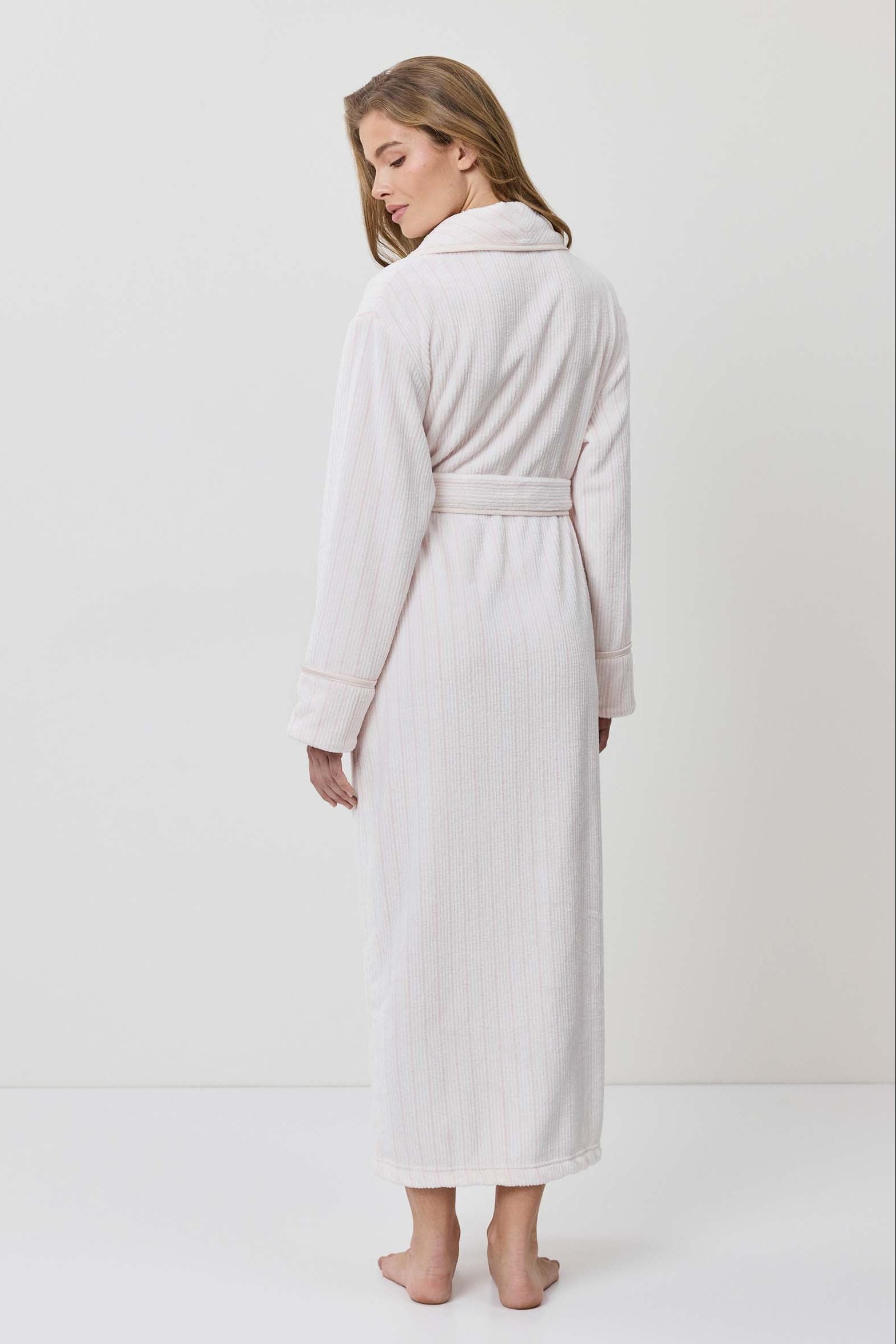 Woman wearing a white robe against a plain background