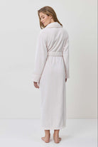 Woman wearing a white robe against a plain background