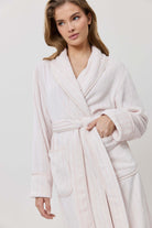 Woman wearing a white robe against a plain background