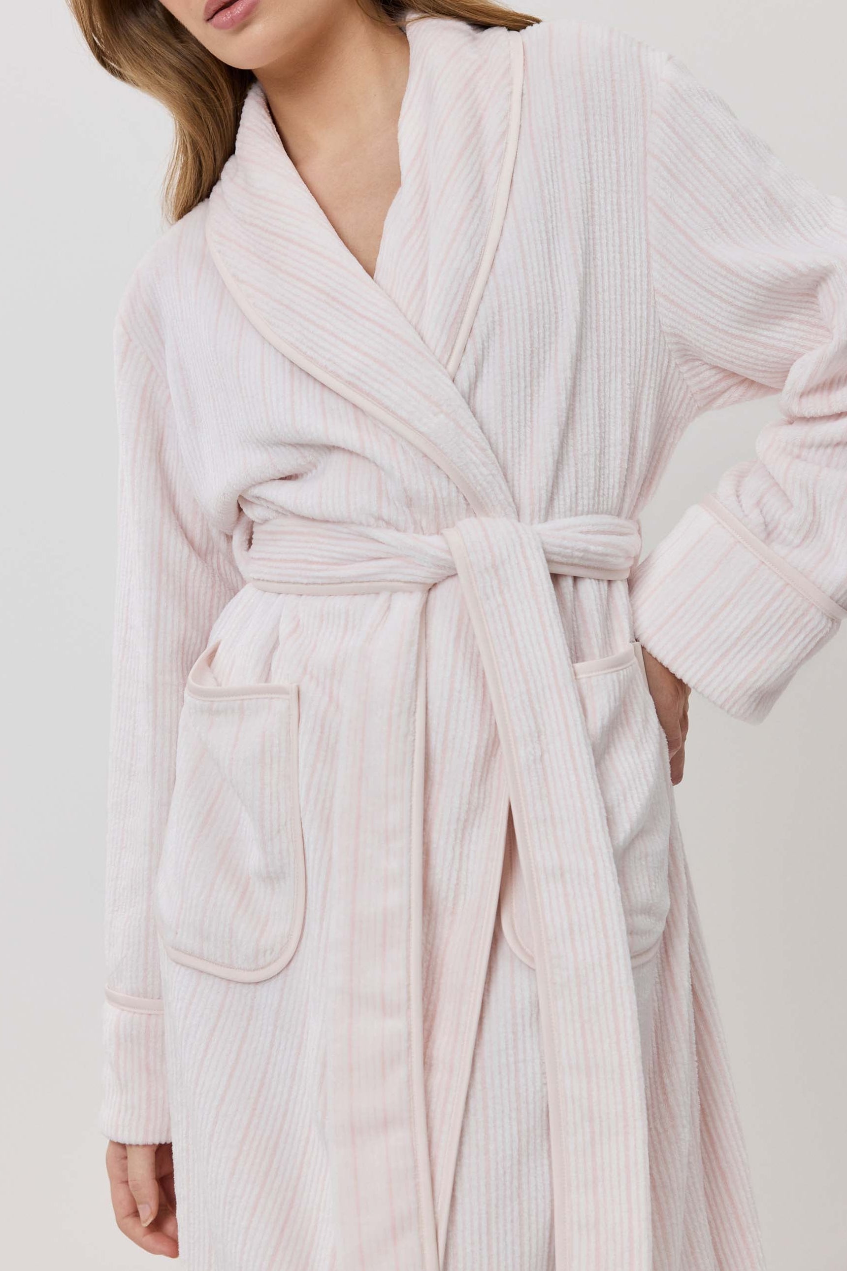 Woman wearing a light pink robe against a white background