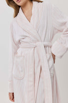 Woman wearing a light pink robe against a white background